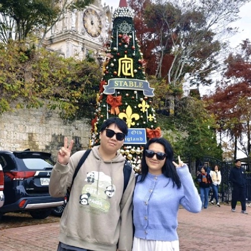 Liang Qian posing with another person by a Christmas tree